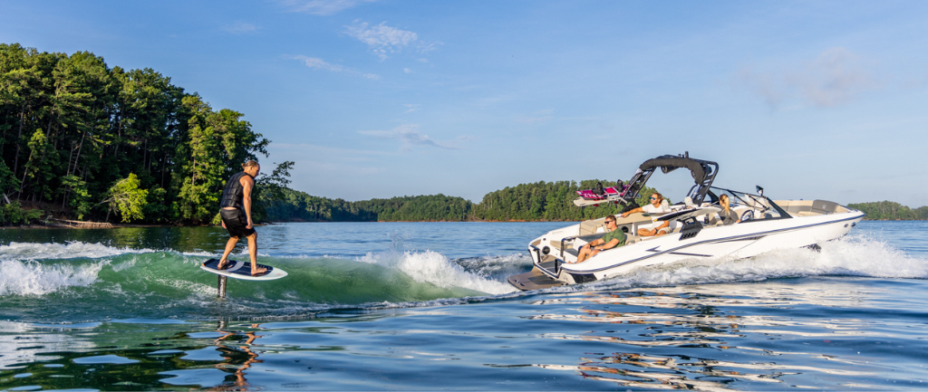 family riding a surf boat on a lake